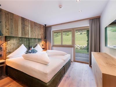 La suite Steintal impresiona con su dormitorio inundado de luz, una acogedora cama doble, mucha madera y vistas a la naturaleza: su refugio elegante en Söll.