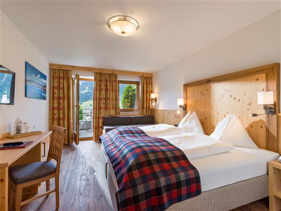 Habitación doble luminosa en el Hotel Alpenpanorama en la región de vacaciones Wilder Kaiser con balcón y vistas a las montañas.