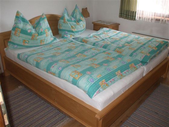Una acogedora habitación con una gran cama doble. La ropa de cama tiene un patrón colorido y las almohadas están dispuestas de manera decorativa.