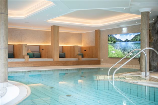 Relájese en la elegante piscina cubierta con cómodas tumbonas, suave iluminación y una atmósfera tranquila, ideal para momentos de bienestar en la región de Wilder Kaiser.