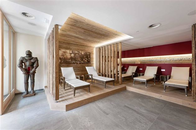 Un moderno espacio de relajación con cómodas tumbonas y cálidos elementos de madera. También se puede ver una estatua de caballero que le da al espacio un carácter único.