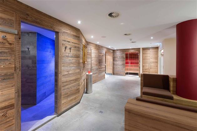 Bienestar con estilo: El área de sauna en el Hotel AlpenSchlössl combina un diseño de madera tradicional con una moderna decoración de color y luz para una experiencia de relajación integral.