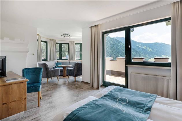 Una habitación moderna con un área de dormir y una sala de estar.  
Grandes ventanas ofrecen una vista de las montañas y proporcionan mucha luz natural.