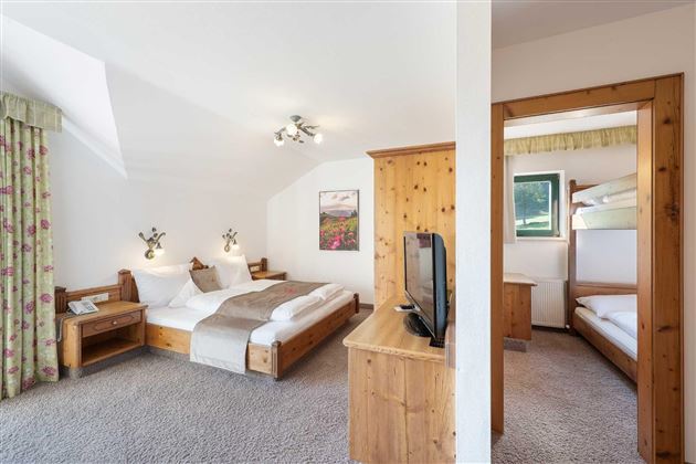 Una habitación moderna con dos camas, un televisor y un acogedor armario de madera.  
Hay una habitación contigua con una litera, ideal para familias.