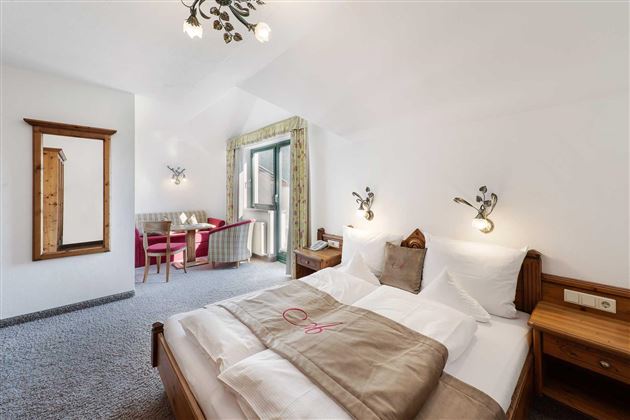 Una acogedora habitación de hotel con cama doble y decoración moderna. Una mesa con sillas y un gran espejo completan el espacio.
