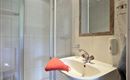 Ein modernes Badezimmer mit einer Dusche und einem Waschbecken. Ein orangefarbenes Handtuch liegt auf dem Waschbecken.
