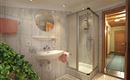 Ein modernes Badezimmer mit einer Dusche und einem Waschbecken. Die Wände sind mit hellen Fliesen verkleidet und es gibt eine schöne Pflanze in der Ecke.