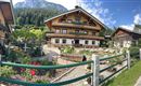 Ein traditionelles alpenländisches Haus mit Holzverkleidung und blühendem Garten.
