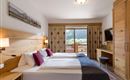 Habitación doble en el Hotel Alpenpanorama en la región de vacaciones Wilder Kaiser con muebles de madera, rincón acogedor y vistas a la naturaleza.