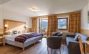 Habitación doble espaciosa en el Hotel Alpenpanorama en la región turística Wilder Kaiser con zona de estar, sofá, escritorio y mucha luz natural.