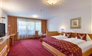 Habitación confort en el Hotel Alpenpanorama en la región de vacaciones Wilder Kaiser con cama boxspring, alfombra roja y acceso al balcón.