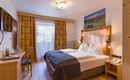 Habitación doble en el Hotel Alpenpanorama en la región turística Wilder Kaiser con detalles de madera, escritorio e iluminación elegante.