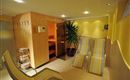 Ein entspannender Wellnessbereich mit einer Sauna und Liegen. Die Wände sind gelb gestrichen und es gibt Pflanzen für eine angenehme Atmosphäre.