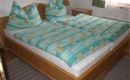 Una acogedora habitación con una gran cama doble. La ropa de cama tiene un patrón colorido y las almohadas están dispuestas de manera decorativa.