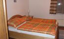 Una acogedora habitación con una cama doble y edredones a cuadros. Las paredes están pintadas de un color claro y hay lámparas de mesita de noche así como cortinas en la ventana.