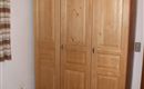 Un armario clásico de madera con tres puertas. El armario está en un dormitorio acogedor.
