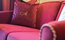Amor por el detalle: La almohada con el logo en la elegante silla tapizada expresa de manera encantadora la firma de la casa.
