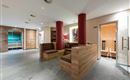 Un moderno spa con revestimientos de madera y cómodas áreas de descanso. Al fondo se puede ver una sauna que invita a la relajación.